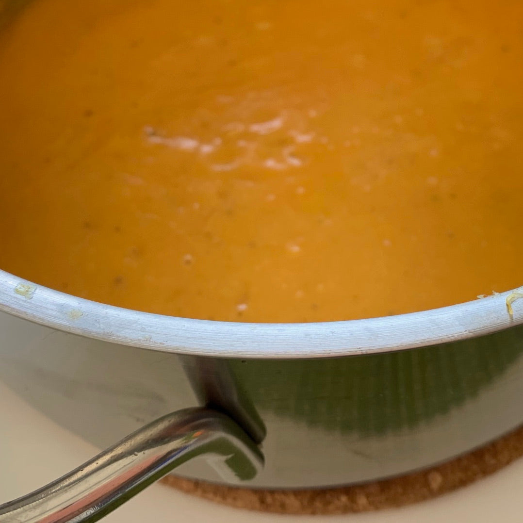 Die orange farbene Suppe in dem Topf ist eine leckerer Süßkartoffel-Bananen-Suppe.