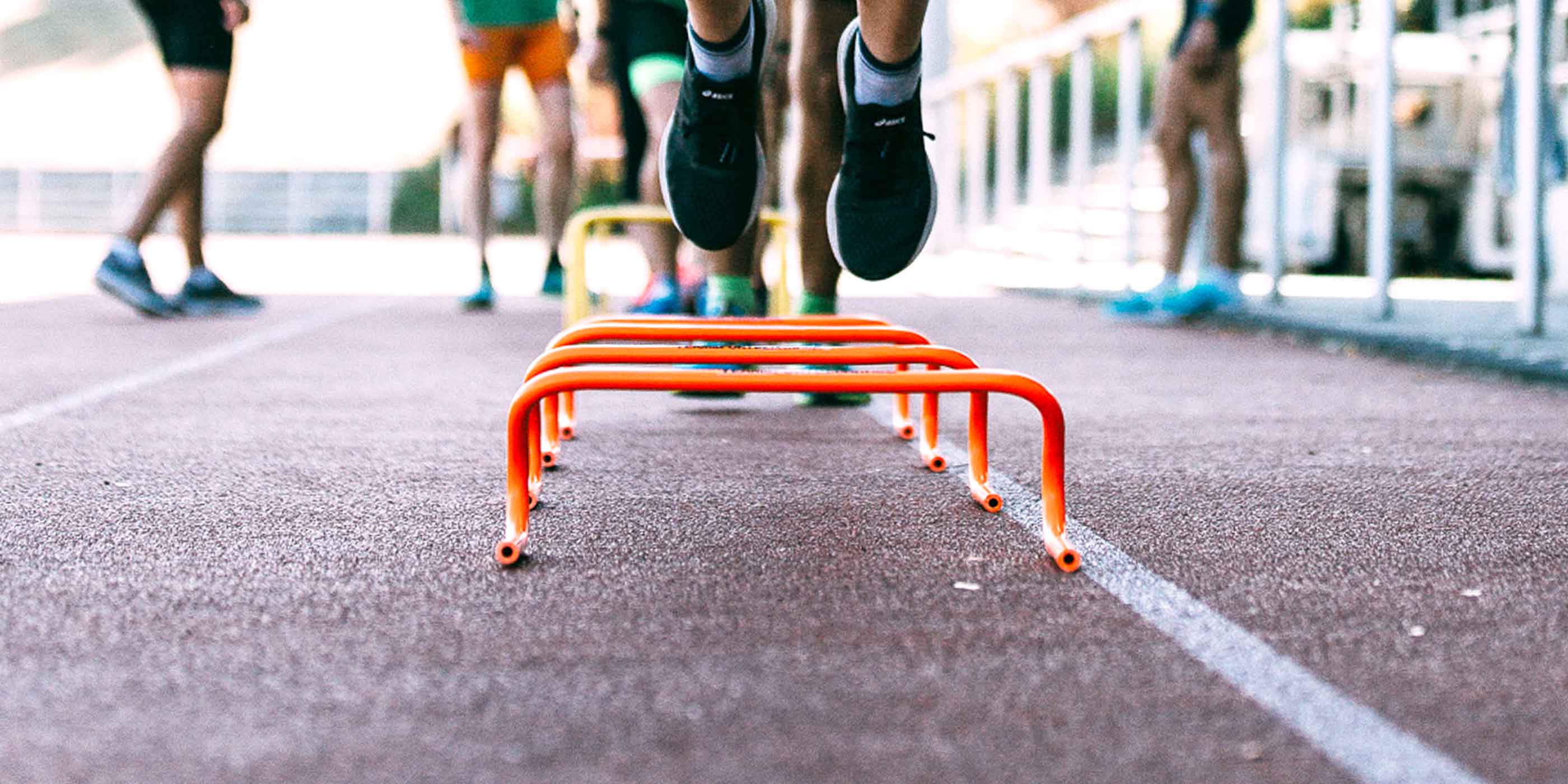 Bei der Lauftrainer Ausbildung beim Laufseminar Laufkurskonzepte springen Läufer und Läuferinnen über eine kleine Hürde