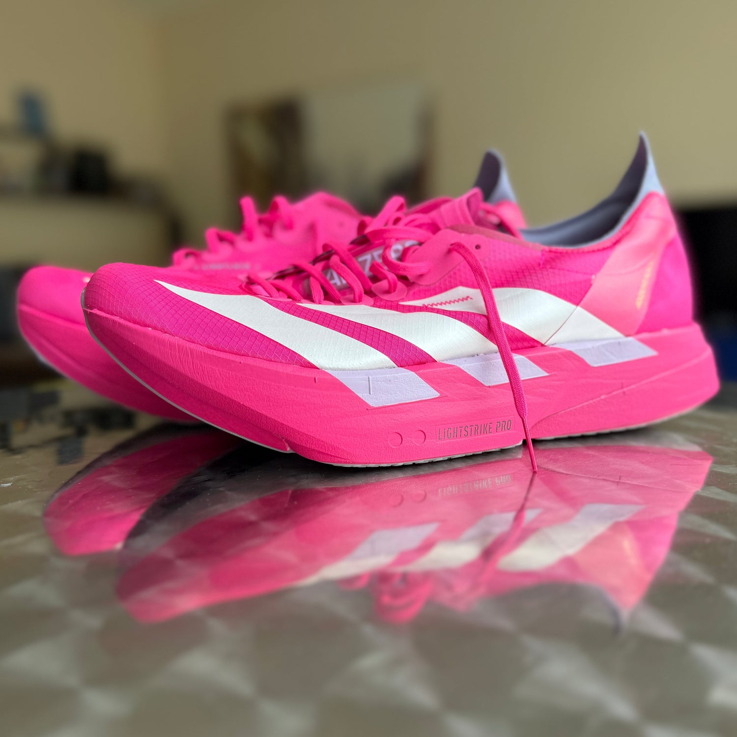 Pink Adidas Carbonschuhe spiegeln sich auf einem Tisch