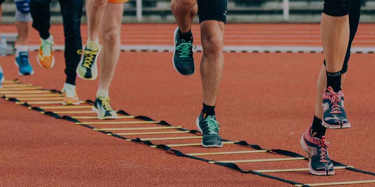 Tipps für Ihr Lauftraining, Ernährung, Gesundheit und mehr – Läufer durchlaufen eine Koordinationsleiter auf der Tartanbahn