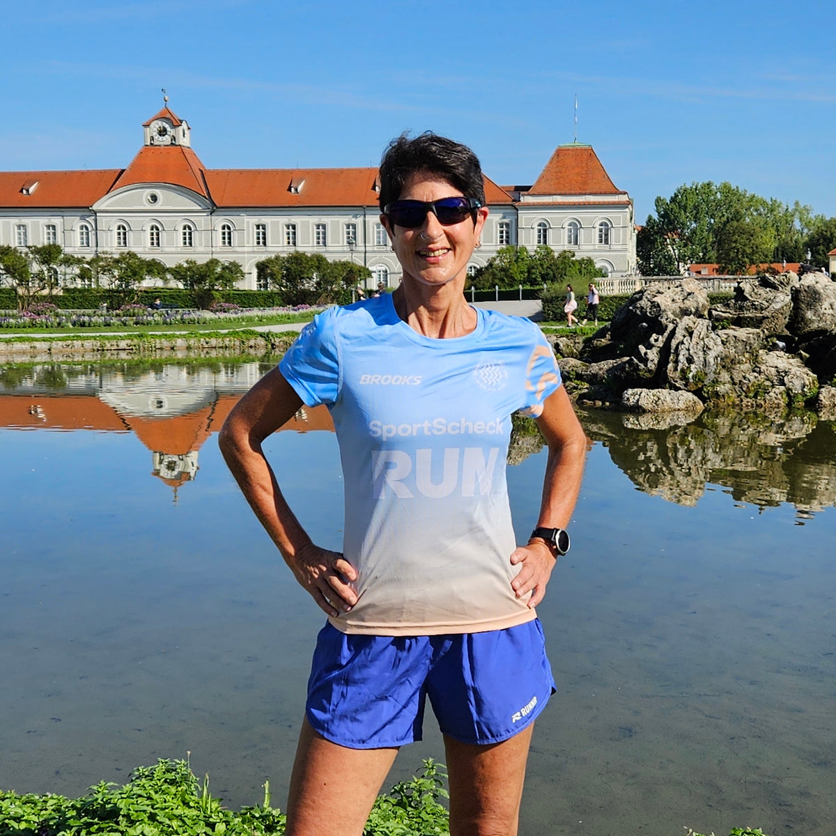 Bianca Winarsky posiert in Laufkleidung vor einem Schloss am See.